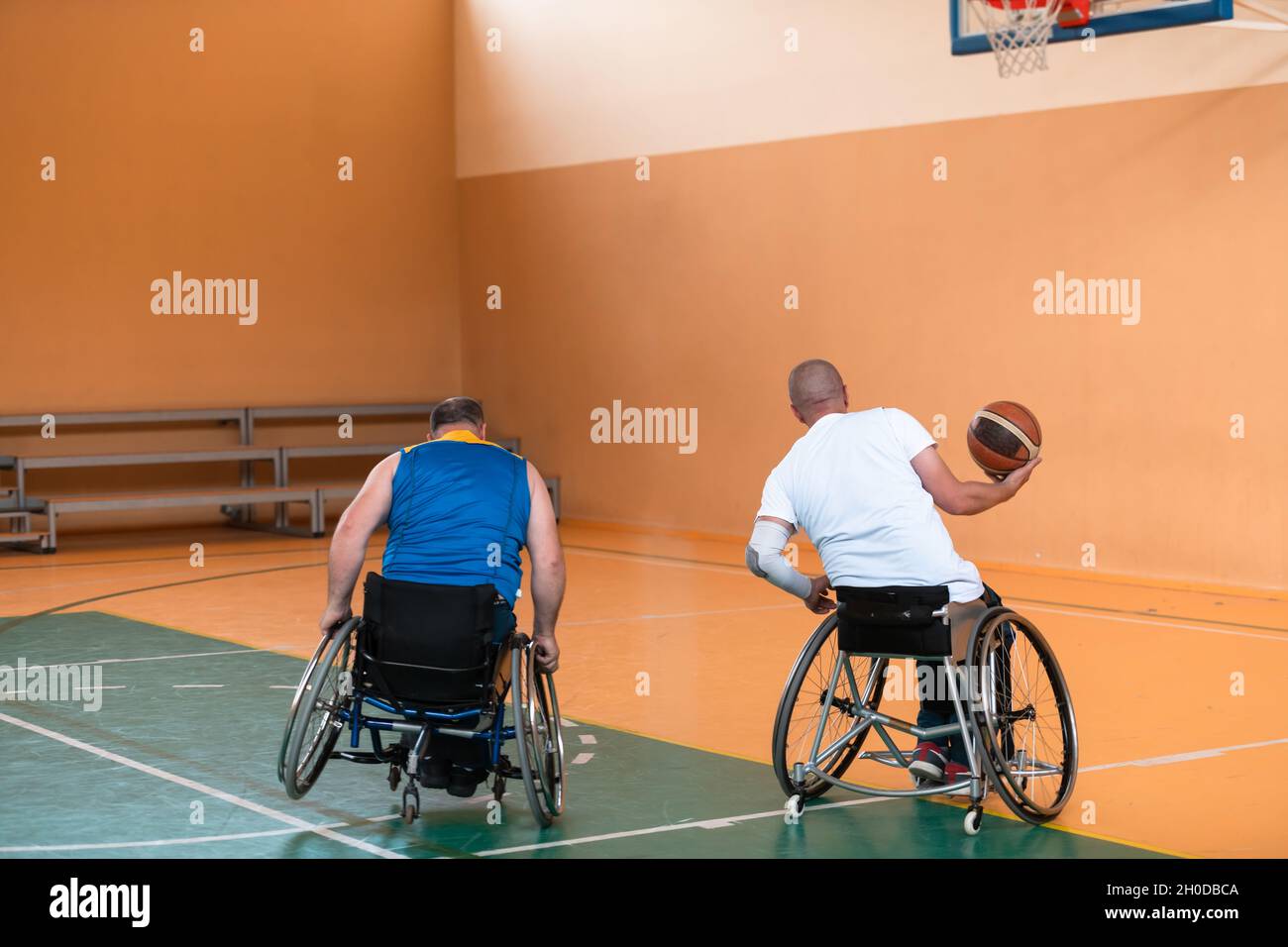 I veterani della guerra disabili hanno mescolato le squadre di pallacanestro di età e di corsa in carrozzina che giocano un match di addestramento in una sala della palestra di sport. Disabili Foto Stock