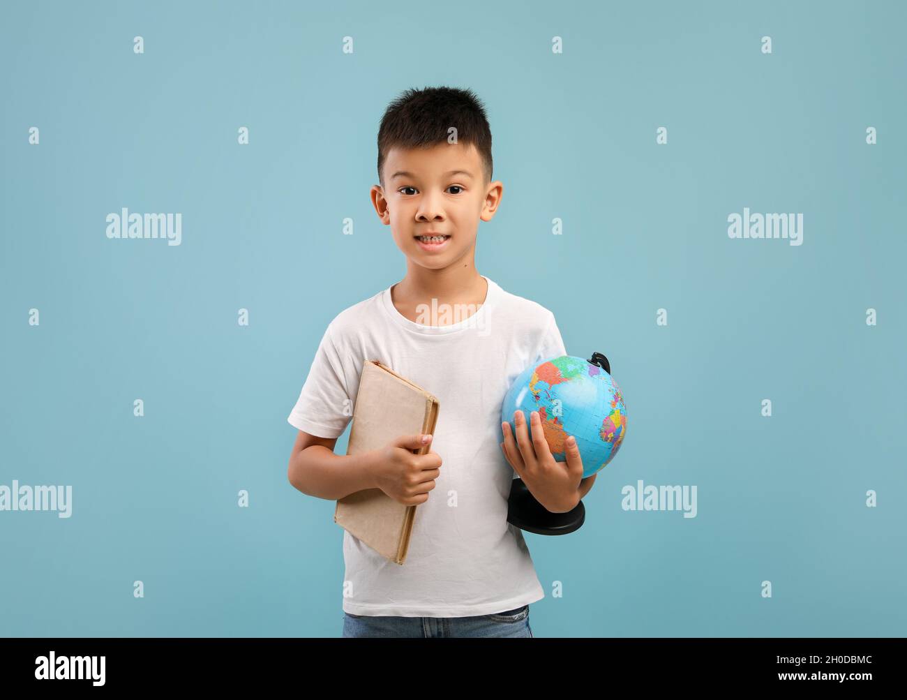 Ritratto di Little Asian Boy Holding Book e World Globe Foto Stock