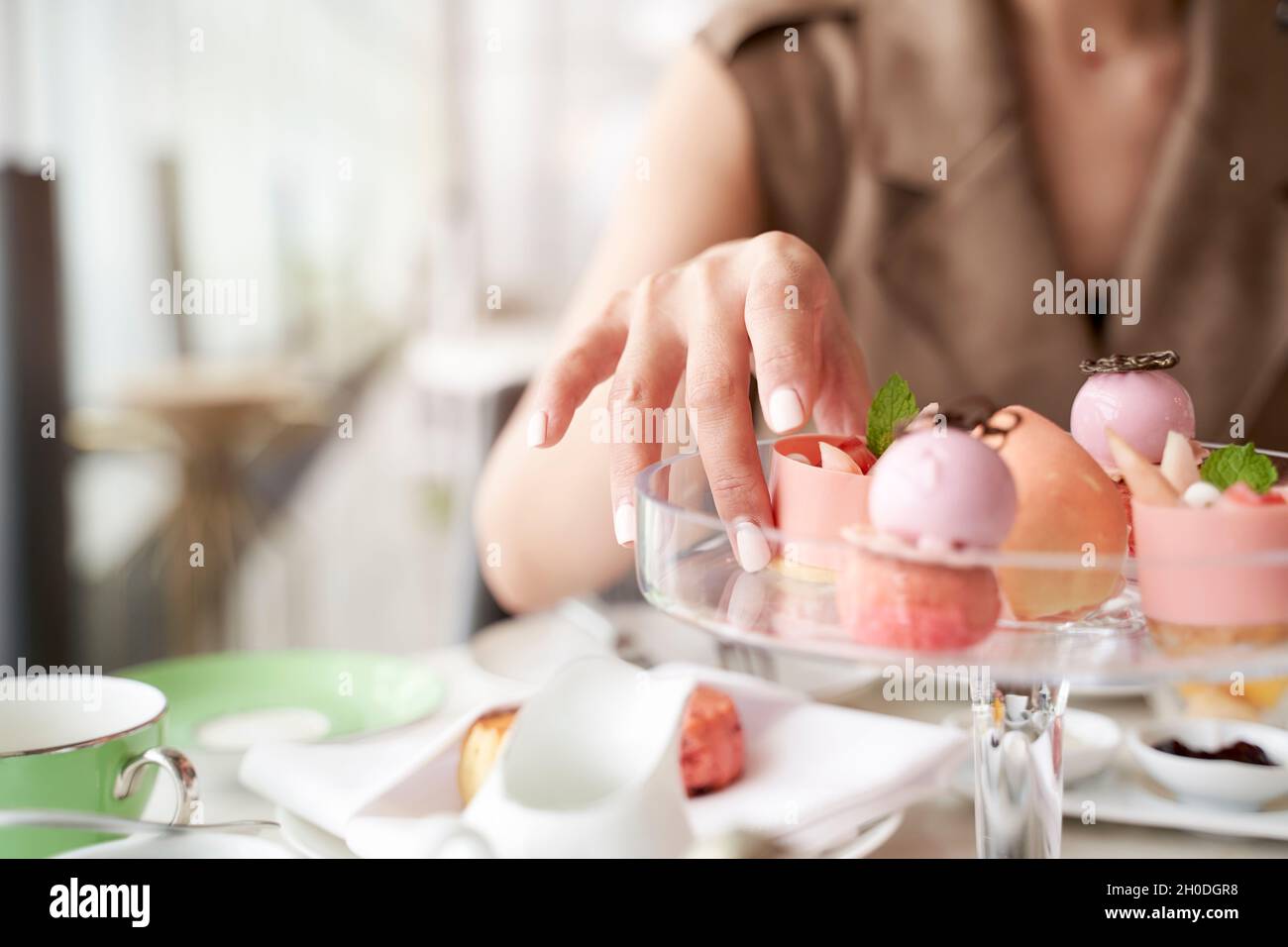 mano di donna asiatica che raccoglie un dessert da un piatto di vetro Foto Stock