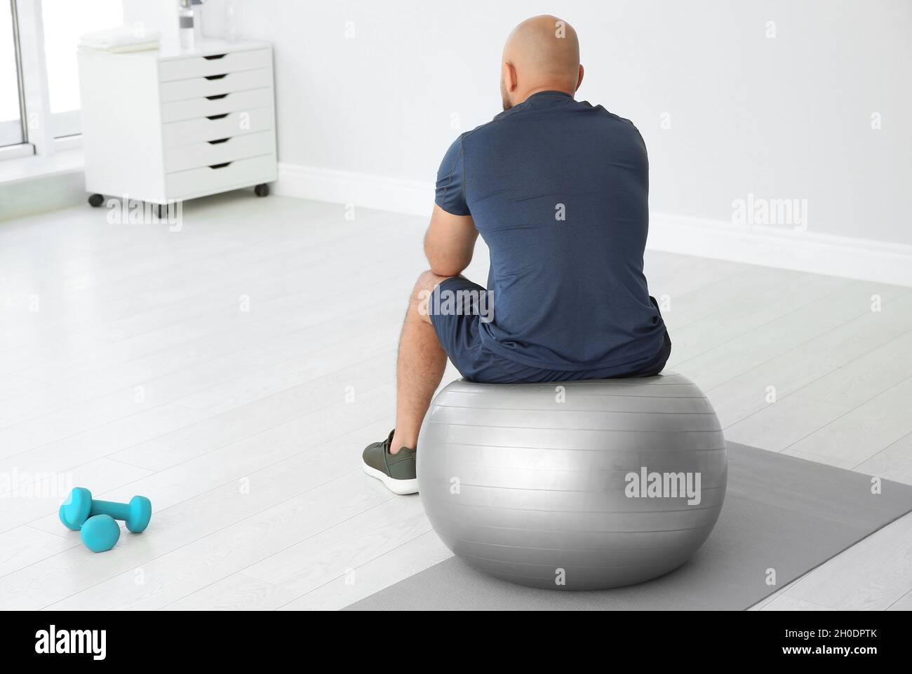 Uomo in sovrappeso stanco seduto sulla palla da fitness in palestra Foto  stock - Alamy