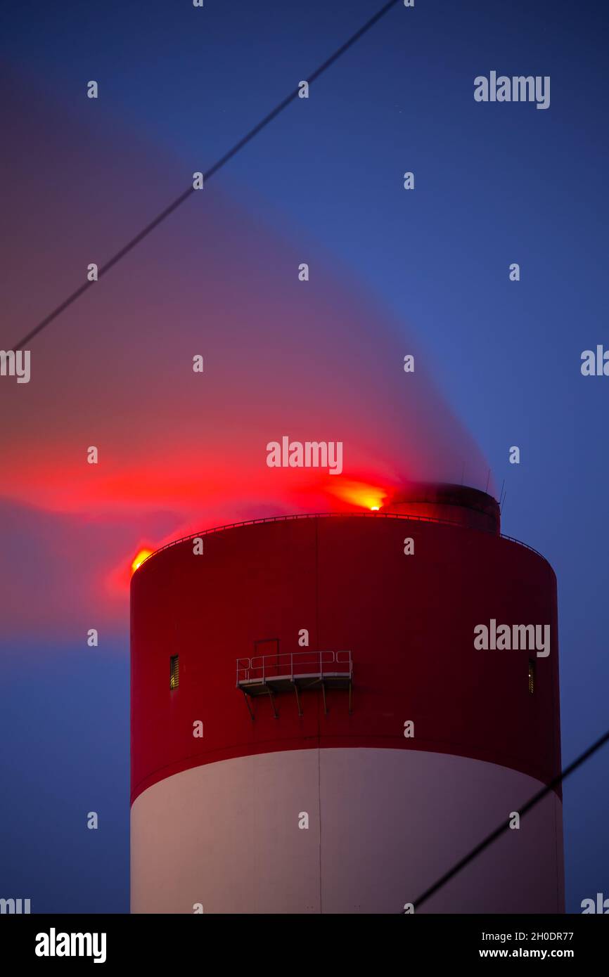 Foto serale della centrale a carbone. Vista sfocata per il fumo che esce dai camini. Luce rossa sulla parte superiore della pila. Foto scattata alla vigilia Foto Stock