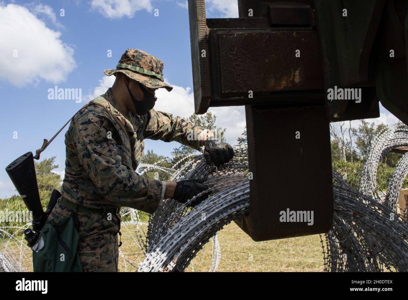 Un US Marine with Combat Logistics Battaglione (CLB) 31, 31st Marine Expeditionary Unit (MEU), scarica il filo di concertina durante un esercizio di assistenza umanitaria straniera (FHA) a Kin Blue, Okinawa, Giappone, 4 febbraio 2021. Il 31 MEU opera a bordo di navi dell'America Expeditionary Strike Group nella settima area di attività della flotta per migliorare l'interoperabilità con gli alleati e i partner e fungere da pronta forza di reazione per difendere la pace e la stabilità nella regione IndoPacifico. Foto Stock