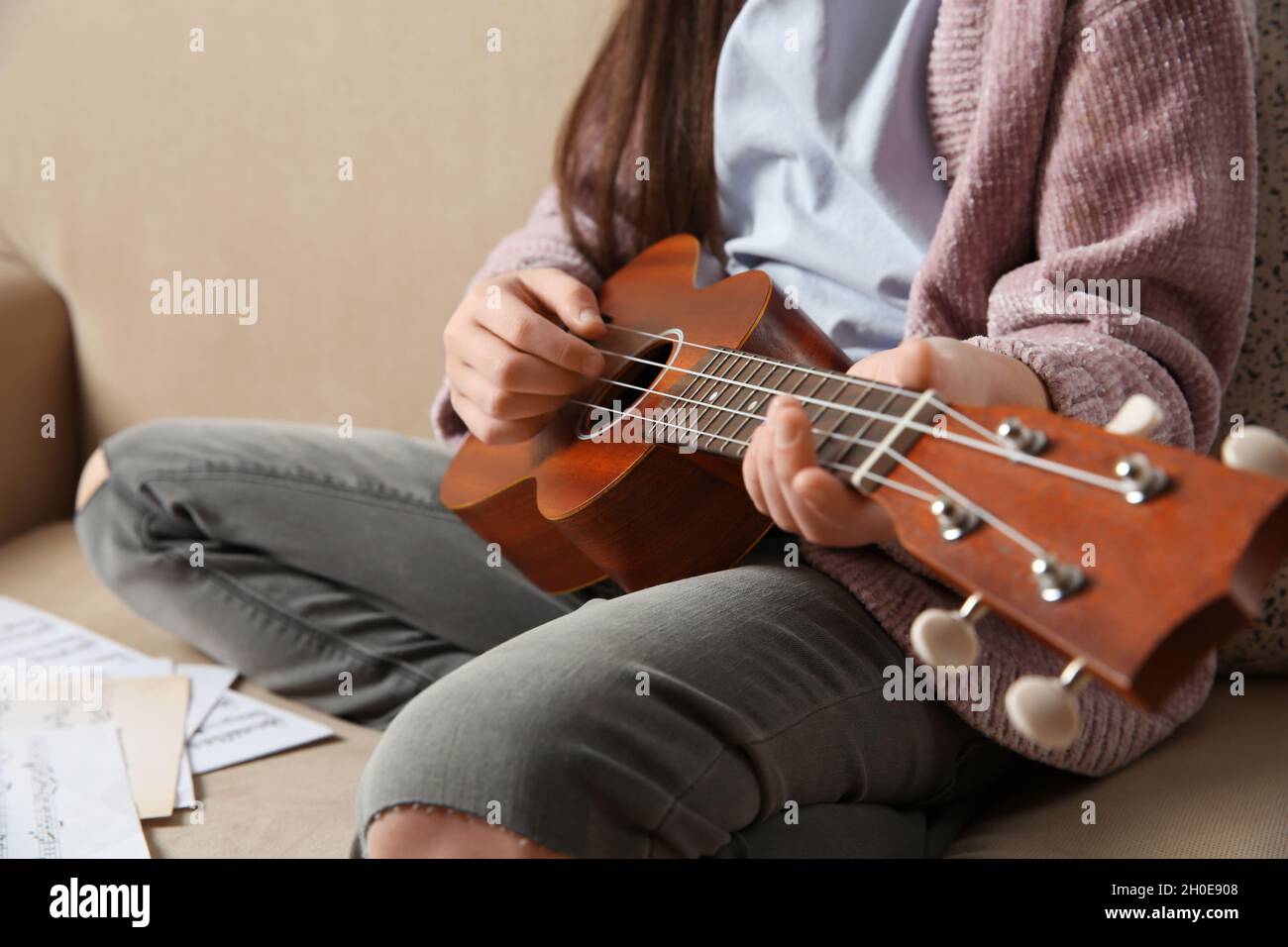 Bambina che suona la chitarra sul divano, primo piano Foto stock - Alamy