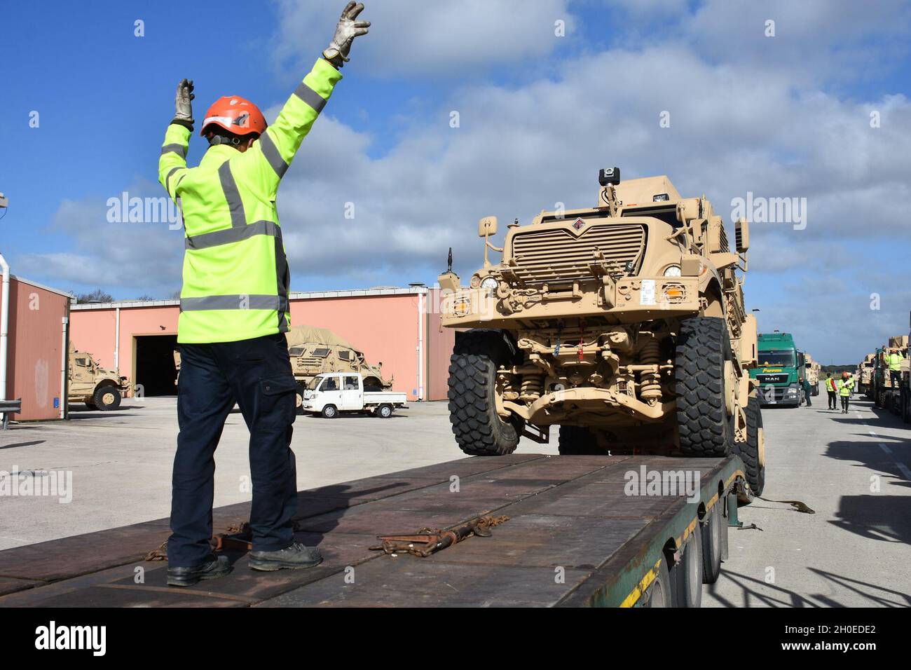 I dipendenti nazionali italiani e statunitensi con il 405o Army Field Support Brigade's Army Field Support Battaglione-Africa caricano più di 100 veicoli protetti da Ambush resistenti alle mine su trattrici trainanti a pianale da consegnare al porto e spedire in un nuovo sito Army Preposition Stock. Foto Stock