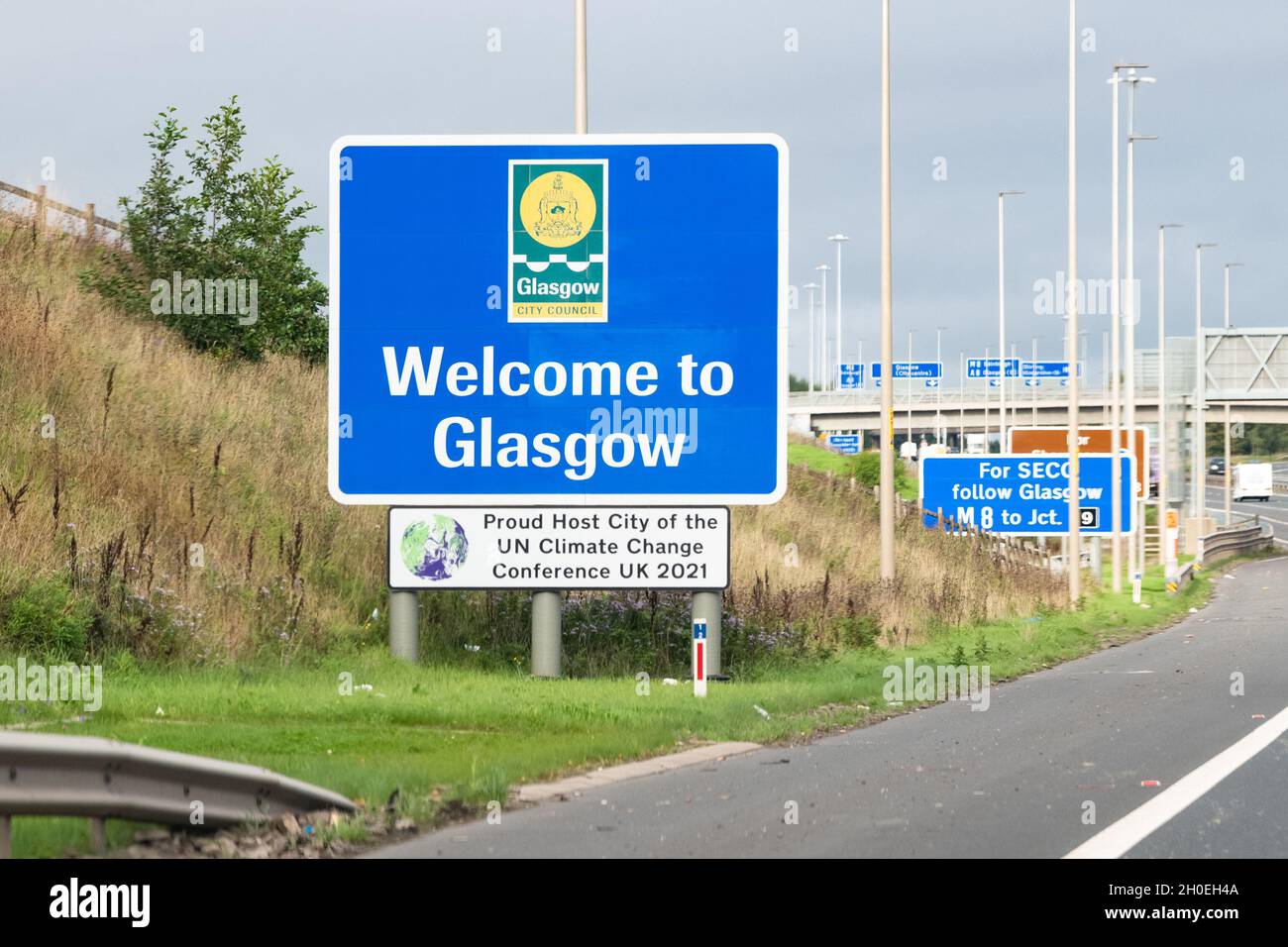 Cop26 Glasgow - Benvenuti a Glasgow 'orgogliosa città ospite della Conferenza ONU sul cambiamento climatico UK 2021' segno vicino all'autostrada M8, Glasgow, Scozia, Regno Unito Foto Stock