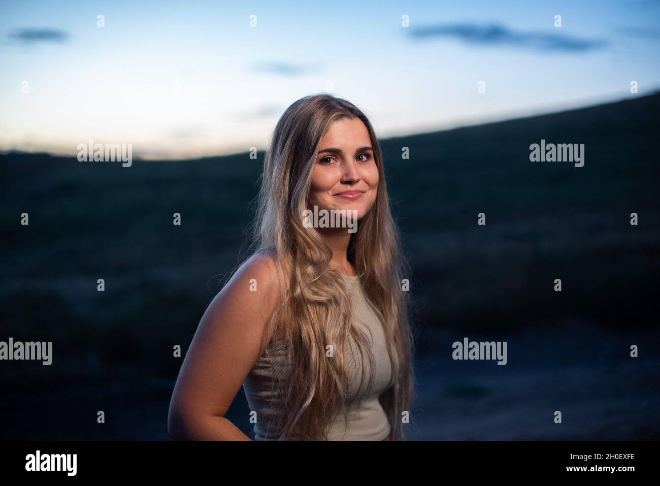 Ritratto di una donna caucasica bionda che sorride mentre diventa buio Foto Stock
