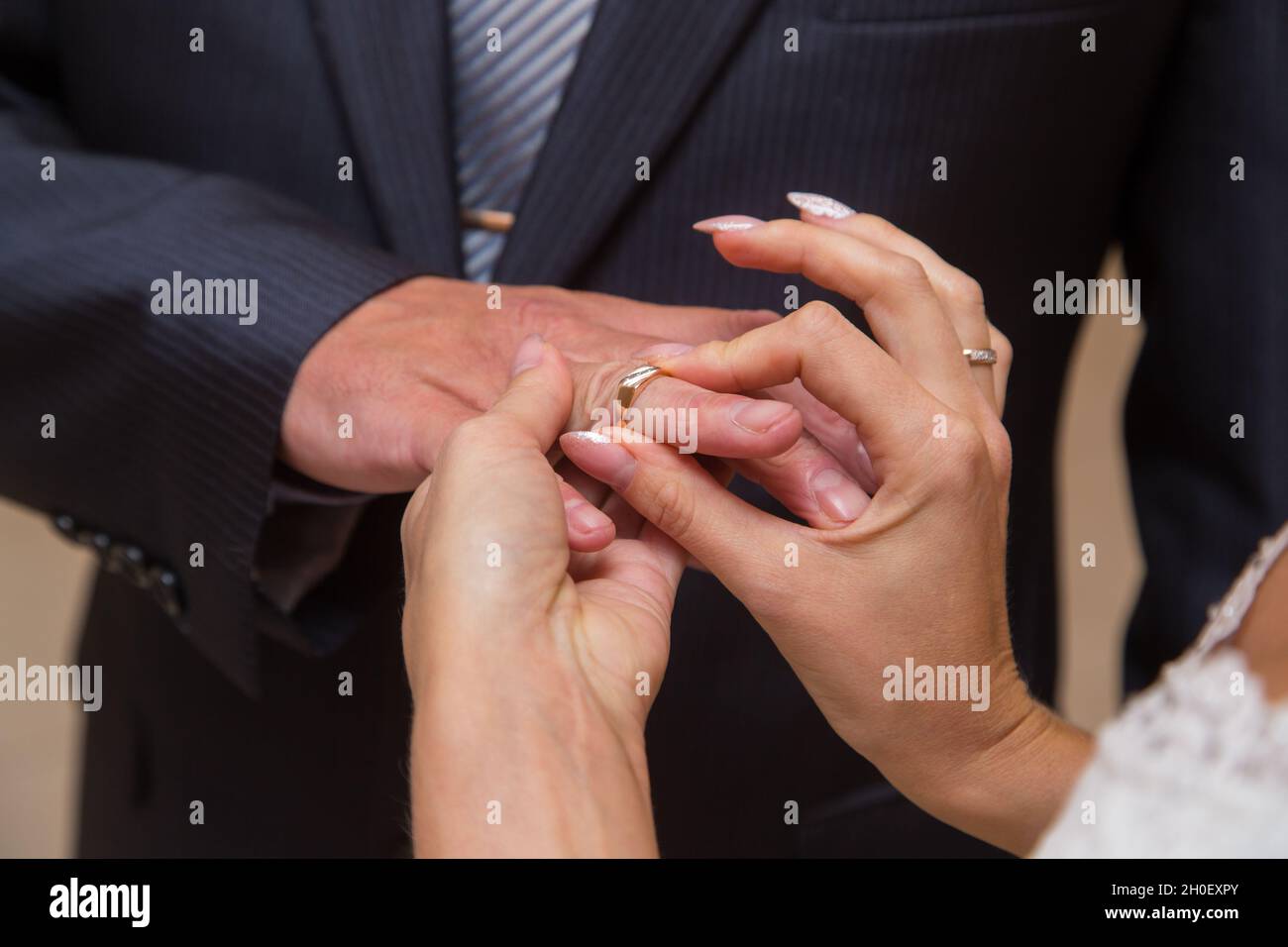 Le mani della ragazza della sposa hanno messo un anello sul dito dell'anello del marito. Grande, chiuso. L'uomo nella giacca. Foto Stock