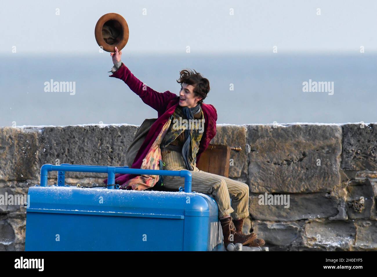 Lyme Regis, Dorset, Regno Unito. 12 ottobre 2021. Scene per il nuovo film Wonka con Timothée Chalamet in fase di film sul porto di Cobb a Lyme Regis in Dorset questo pomeriggio. Timothée Chalamet, che sta giocando il giovane Willy Wonka, è visto in sella a un tetto di furgoni. Picture Credit: Graham Hunt/Alamy Live News Foto Stock