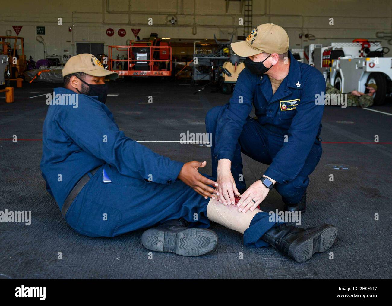 CITTÀ DEL CAPO, Sudafrica (dal 22, 2021) Aviation Boatswain’s Mate (Aircraft Handling) di seconda classe Adam Insley, Right, simula la fornitura di aiuti a Aviation Boatswain’s Mate (Airman Walter Shaw) durante un’esercitazione per incidenti di massa nella baia di hangar della base del Mare di Expeditionary USS Hershel “Woody” Williams (ESB 4) a Città del Capo, Sudafrica, 22 febbraio 2021. Hershel “Woody” Williams opera nella Sixth Fleet statunitense per condurre una formazione di interoperabilità e costruire partnership strategiche con i partner africani. Foto Stock