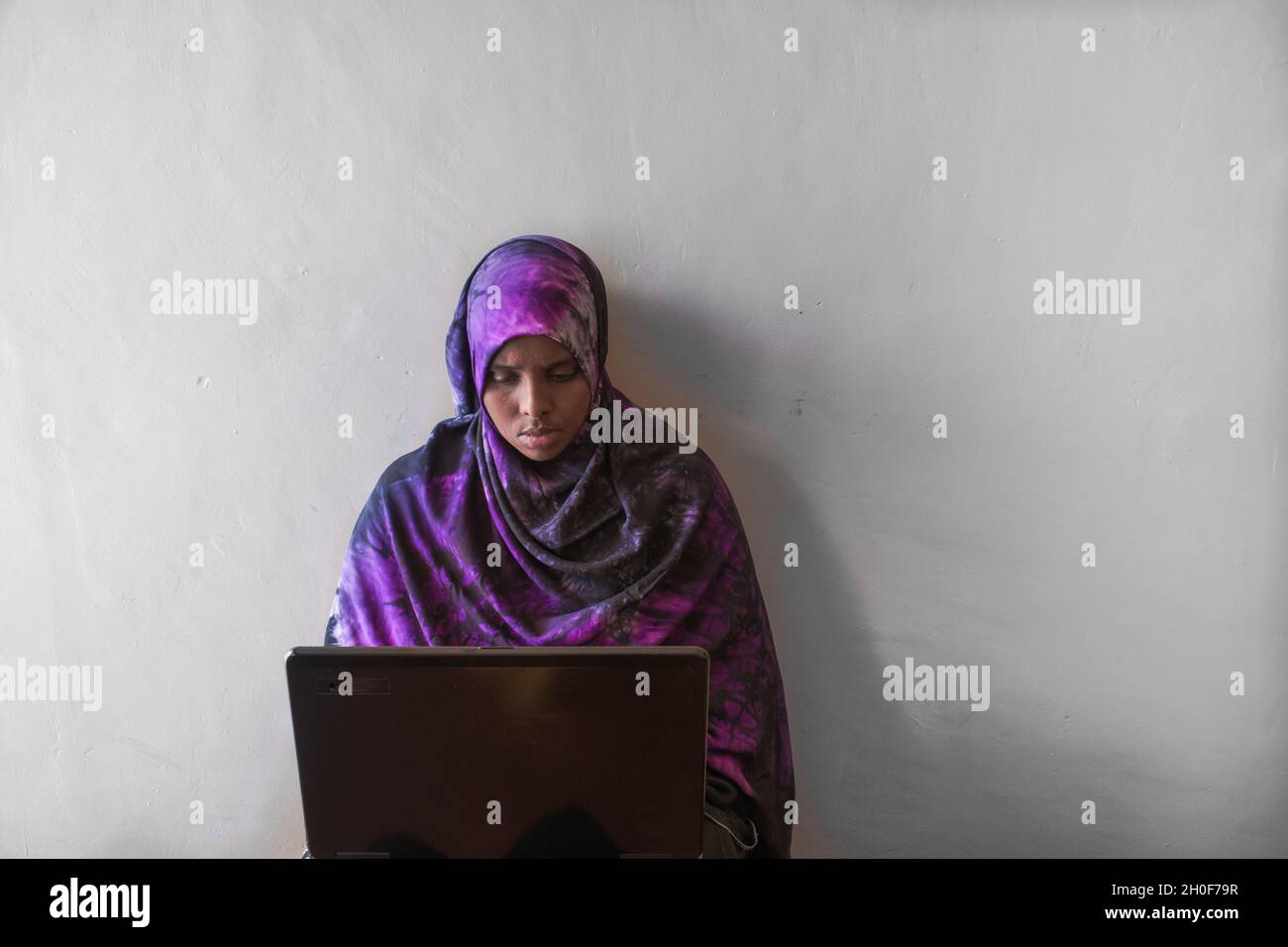 Giovane donna keniana musulmana che lavora sul suo computer da casa. Covid 19 ha fatto pensare a molte persone di lavorare da casa. Foto Stock