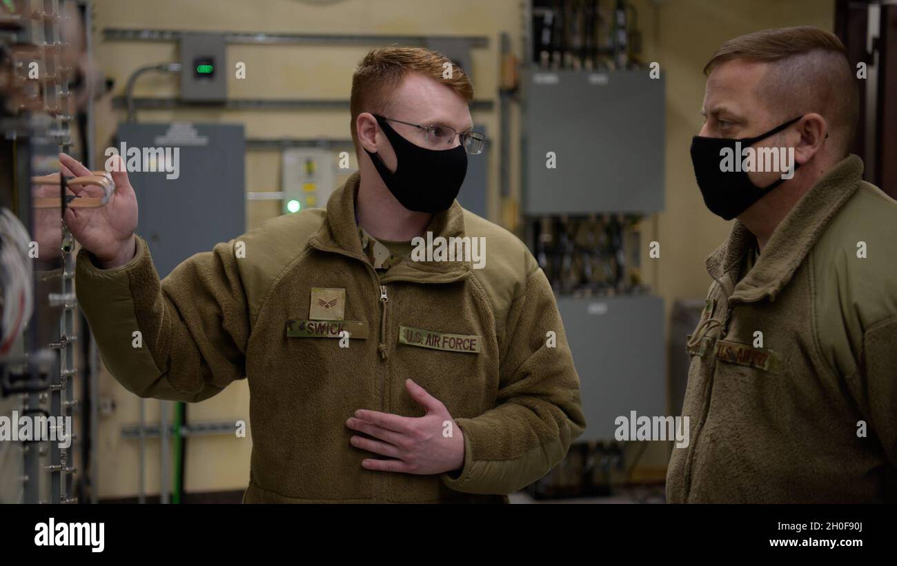 US Air Force Senior Airman coda Swick, a sinistra, un 35esimo tecnico del sistema di trasmissione a radiofrequenza Squadron di comunicazione, presenta una patch panel al Colon. Jesse J. Friedel, il 35esimo comandante della Fighter Wing, durante una passeggiata Wild Weasel presso il sito di comunicazione satellitare, Misawa Air base, Giappone, 23 febbraio 2021. Il segnale a frequenza intermedia scorre nel pannello patch, che combina discretamente più segnali in uno e invia effettivamente quel segnale ad un'antenna satellitare. Foto Stock