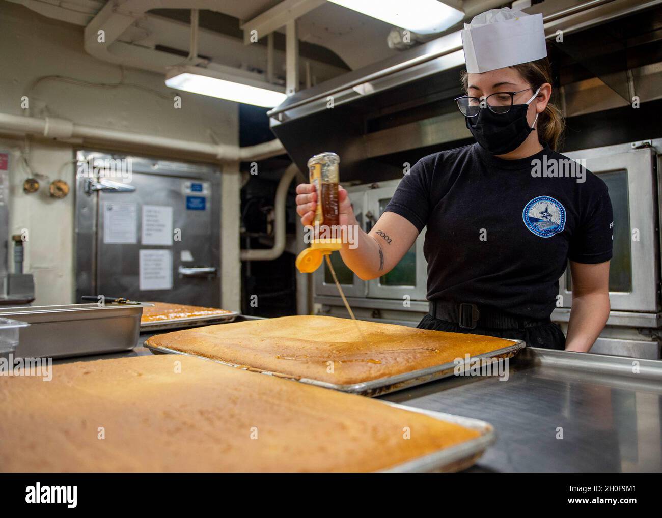 210223-N-EH998-1021 PORTSMOUTH, Virginia (Gen. 8, 2021) Specialista culinario Seaman Sarah Pacheco, da Denton, Texas, mette il miele sul pane di mais a bordo della portaerei USS George H. W. Bush (CVN 77). GHWB è al cantiere navale di Norfolk che sta subendo la sua disponibilità incrementale pianificata di docking. Foto Stock