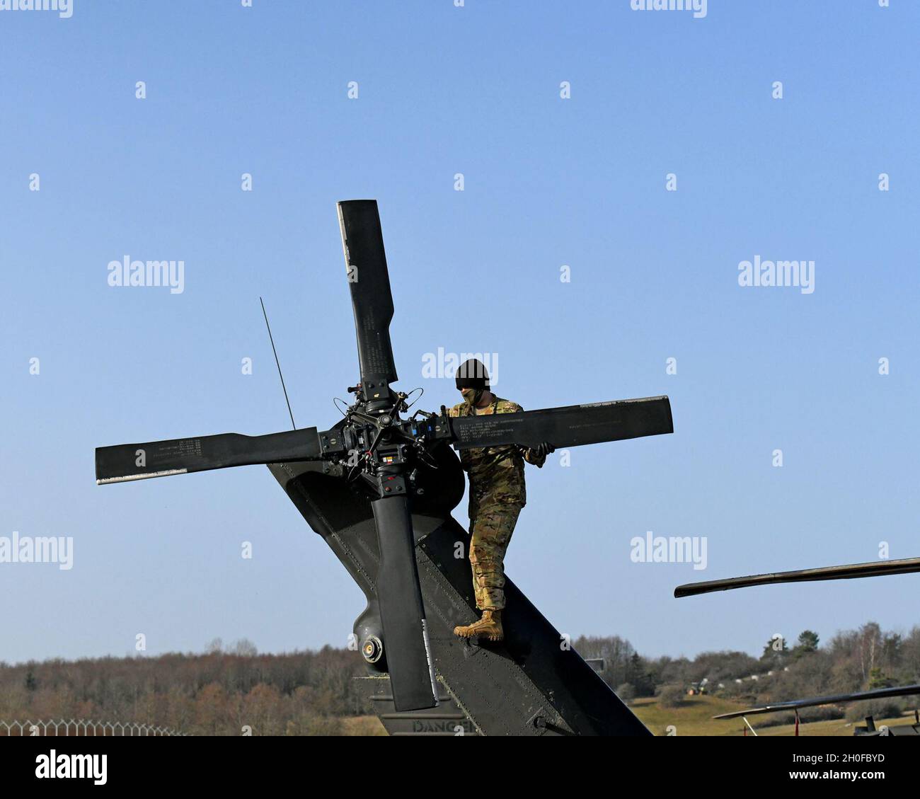 Vredenburg con Charlie Company, 1° Battaglione, 214° Regiment Aviazione, 12° Brigata Aviazione da combattimento, ruota le pale del rotore di coda per condurre un'ispezione completa delle condizioni generali e della sicurezza di ciascuna pala durante le ispezioni pre-volo, Baumholder manovrare Training Area, Germania 24 febbraio 2021. Foto Stock