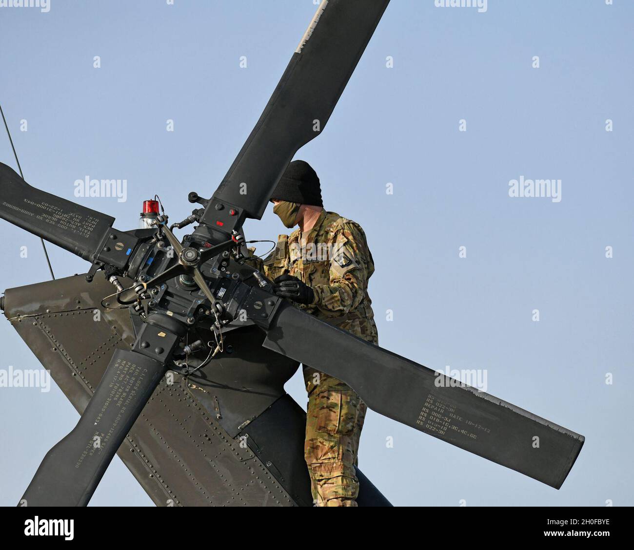 Vredenburg con Charlie Company, 1° Battaglione, 214° Regiment Aviazione, 12° Brigata Aviazione da combattimento, ruota le pale del rotore di coda per condurre un'ispezione completa delle condizioni generali e della sicurezza di ciascuna pala durante le ispezioni pre-volo, Baumholder manovrare Training Area, Germania 24 febbraio 2021. Foto Stock