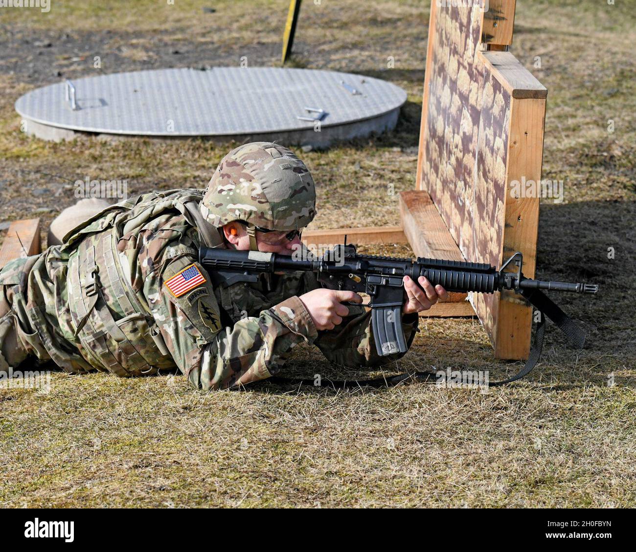 SGT. Prima classe Justin S. Rorex con 1 ° battaglione, 214 reggimento di aviazione, 12 ° combattimento brigata di aviazione, 'Wings of Victory,' durante un esercizio di fuoco dal vivo con M4 Carbine, subito dopo il fuoco, con un caso espulso a mezz'aria. Baumholder Maneuvre Training Area, Range 21, Germania 24 febbraio 2021. Foto Stock