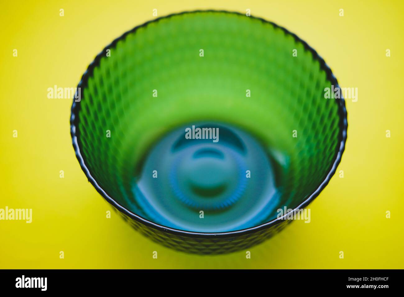 Recipiente in vetro blu su un tavolo giallo. Mescolando i colori blu e giallo si ha una tinta verde. Foto Stock