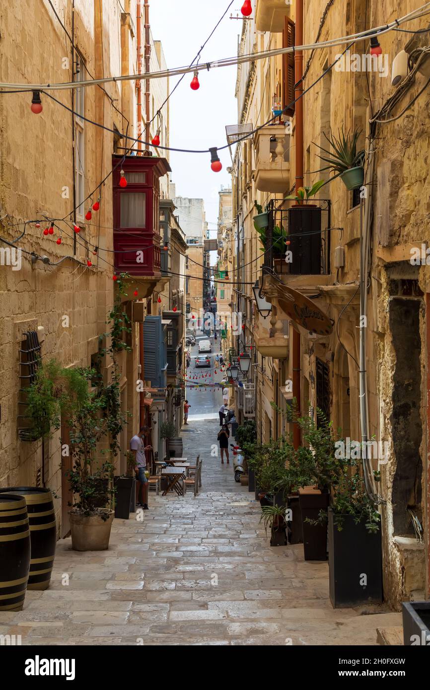 Tipica architettura stradale della Valletta con tradizionali balconi recintati in legno maltese e strada in salita, bulbi Foto Stock