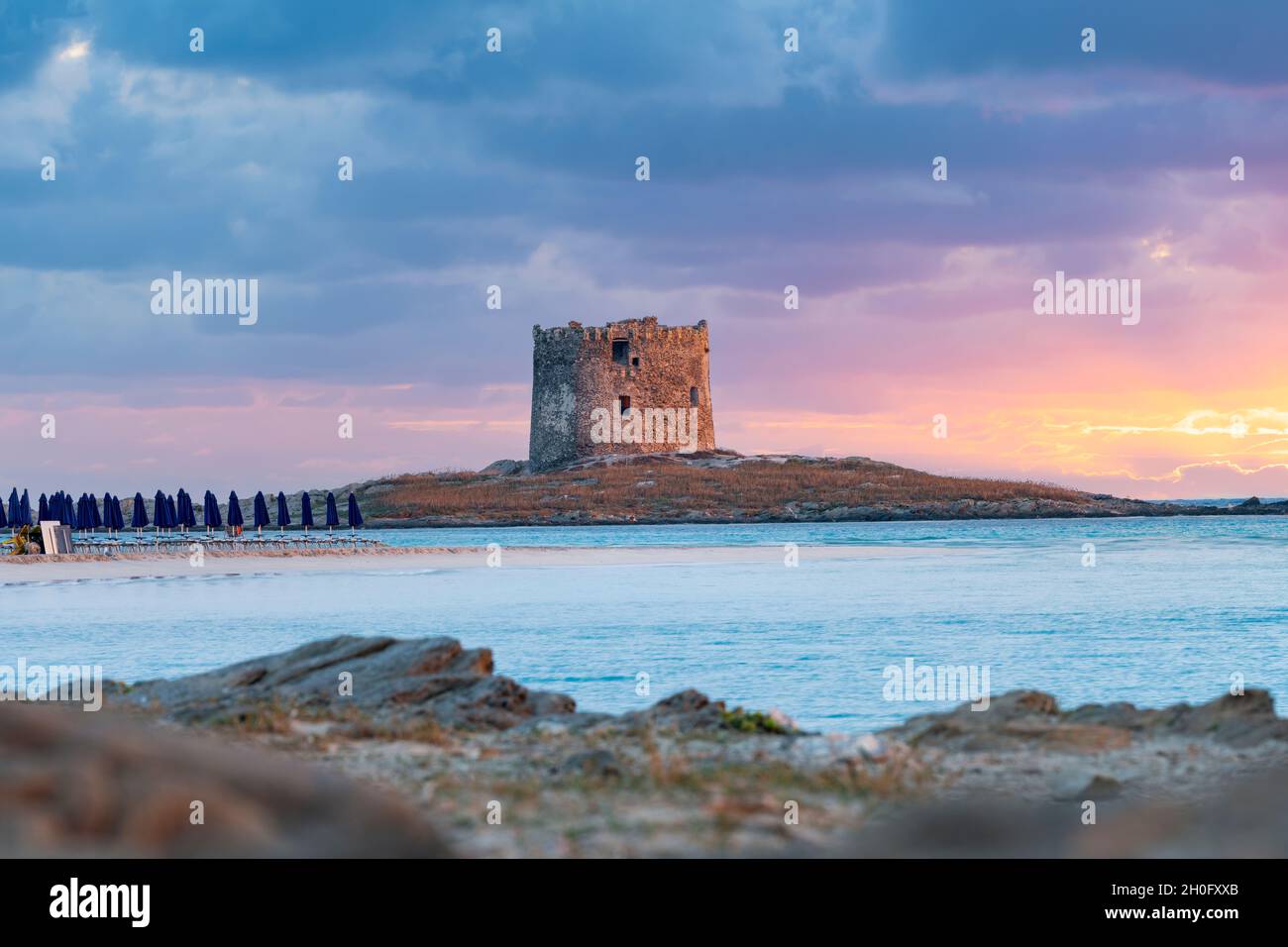 Splendida alba sulla Torre Aragonese e sulla spiaggia la Pelosa bagnata da una tranquilla acqua turchese. Spiaggia la Pelosa, Stintino, Sardegna nord-occidentale. Foto Stock