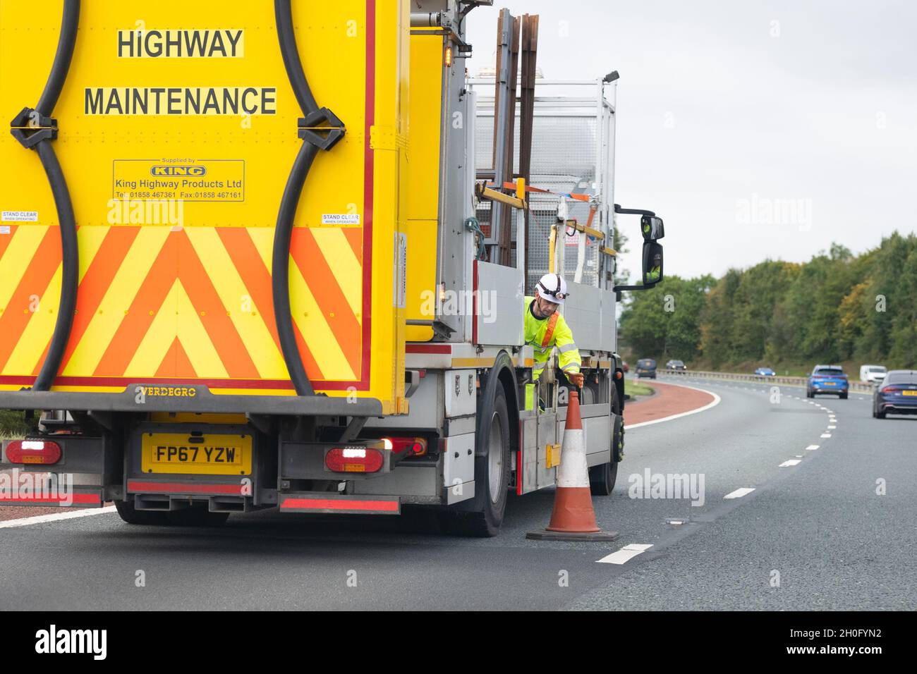 Operatore che raccoglie manualmente i coni stradali sull'autostrada del Regno Unito Foto Stock
