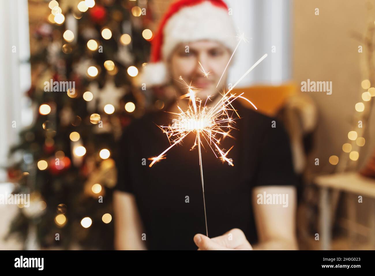 Uomo sorridente in rosso santa cappello o cappuccio che tiene bruciante  Natale o Capodanno luci scintillanti
