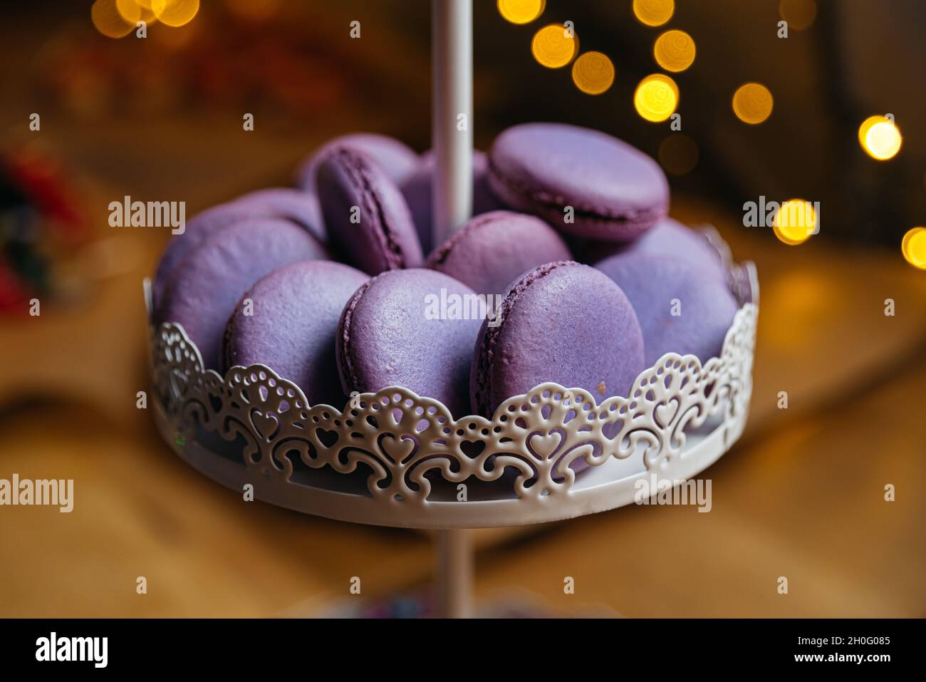 Macaroni lilla su un banco da dessert. Sullo sfondo, un effetto bokeh dalle luci gialle. Foto Stock