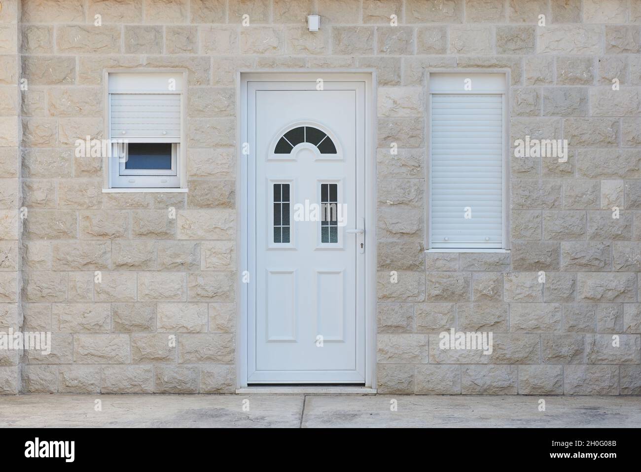 Porta d'ingresso bianca e muro di pietra in un edificio residenziale Foto Stock