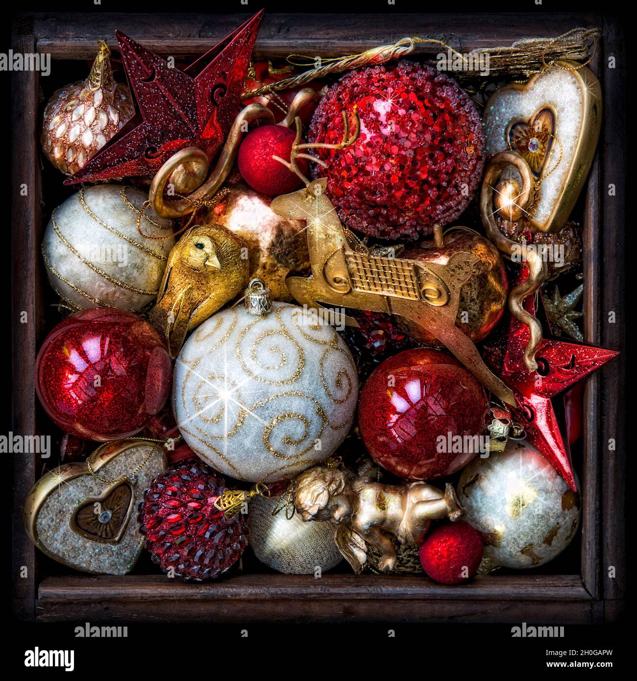 Scatola di legno di decorazioni graziose dell'albero di Natale in rosso, oro e bianco. Processato per dare un effetto leggermente surreale e luminoso Foto Stock