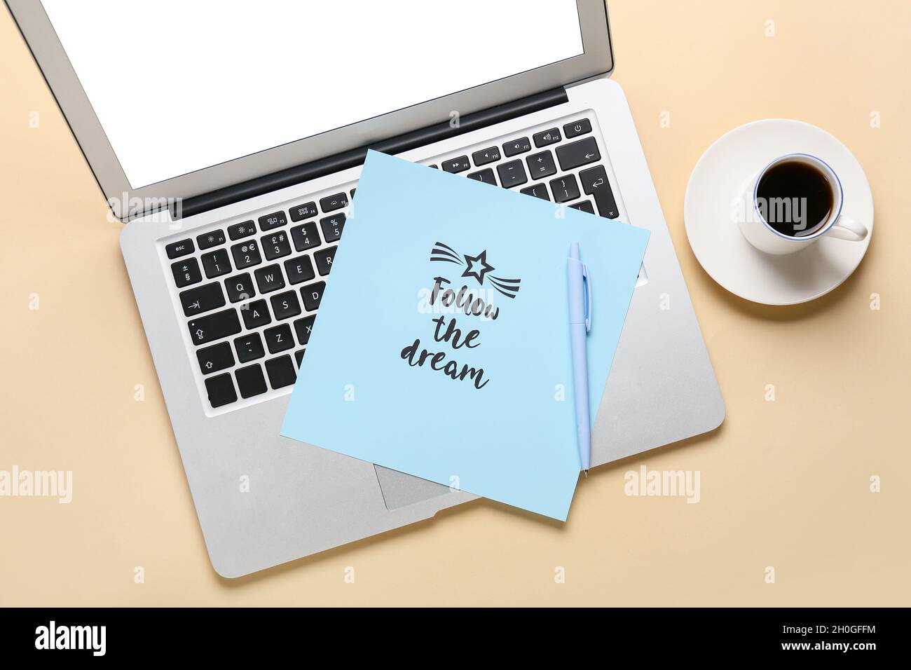 Un foglio di carta con testo SEGUE IL SOGNO, un computer portatile e una tazza di caffè su sfondo chiaro. Obiettivi del nuovo anno Foto Stock