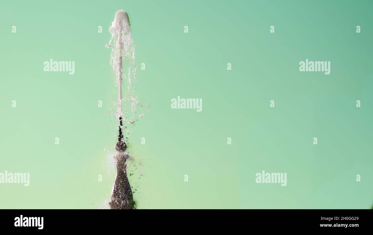 Fontana con liquido chiaro brillante su sfondo smeraldo chiaro Foto Stock