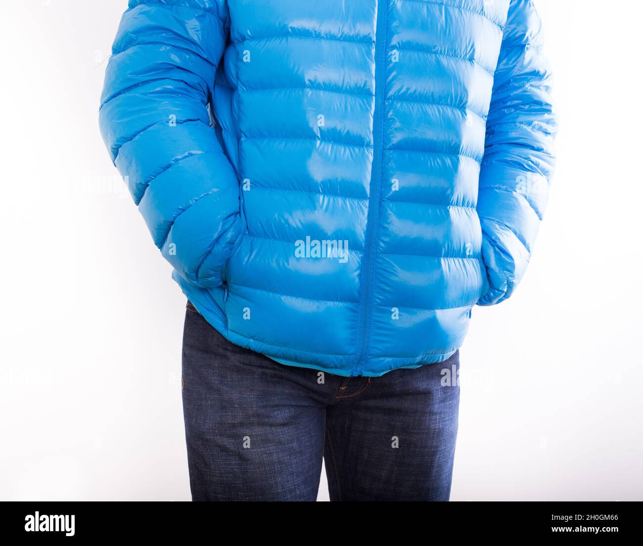 Giovane uomo in giacca di piume blu e in jeans isolato su sfondo bianco  Foto stock - Alamy