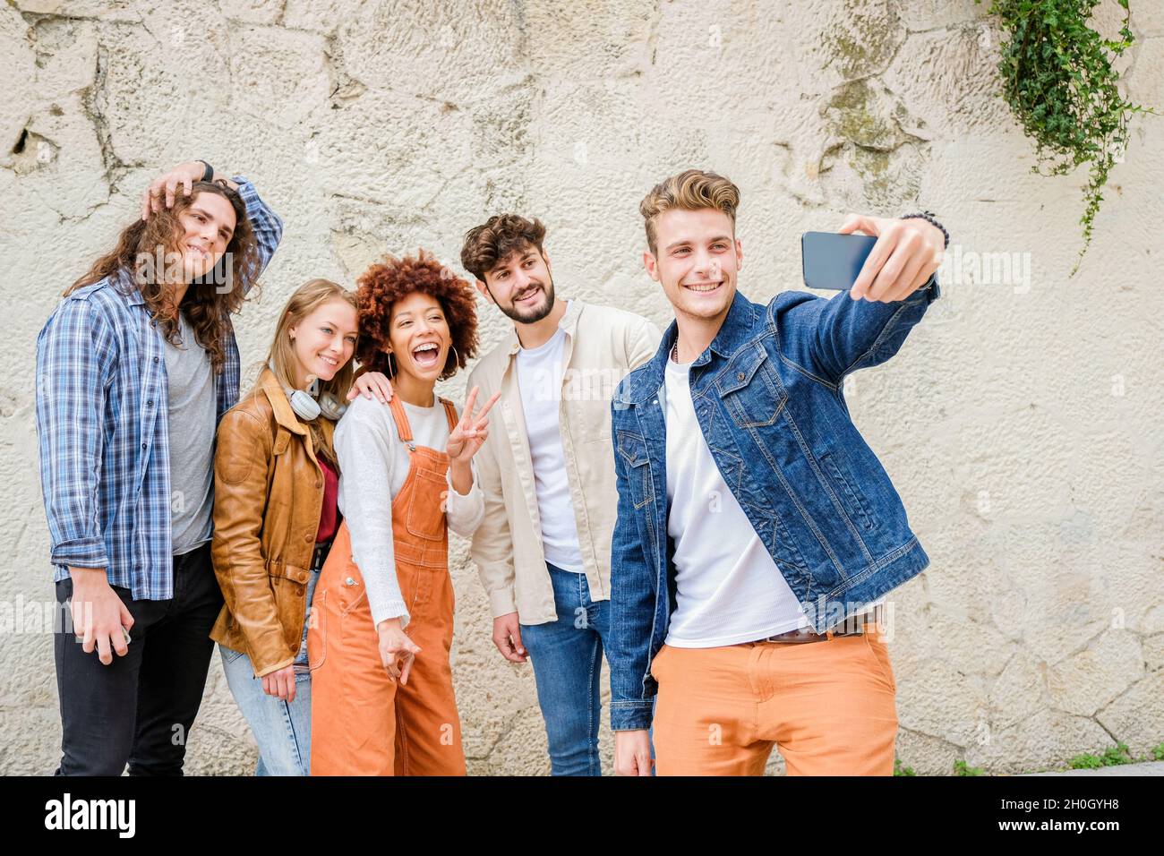 Giovani felici che prendono selfie in città - multirazziale gruppo di amici sta scattando una foto guardando la macchina fotografica Foto Stock
