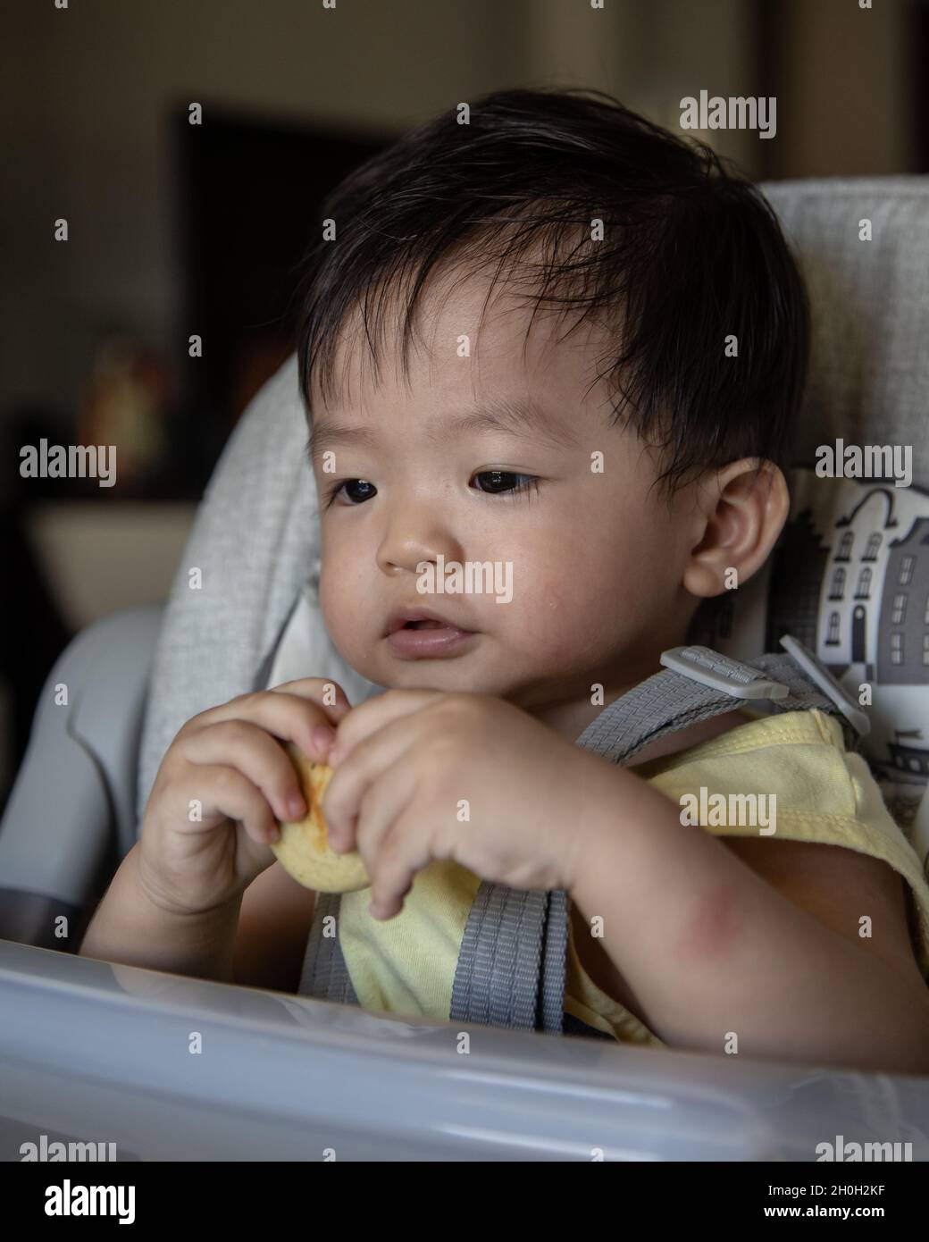 Adorabile gioioso e felice bambino cinese di 1 anno di età che mangiano  mentre si siede sulla sedia del bambino Foto stock - Alamy