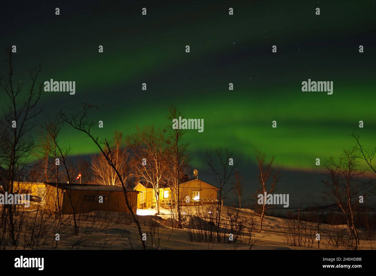 aurora boreale su case luminose, Abisko, Parco Nazionale, Svezia Foto Stock