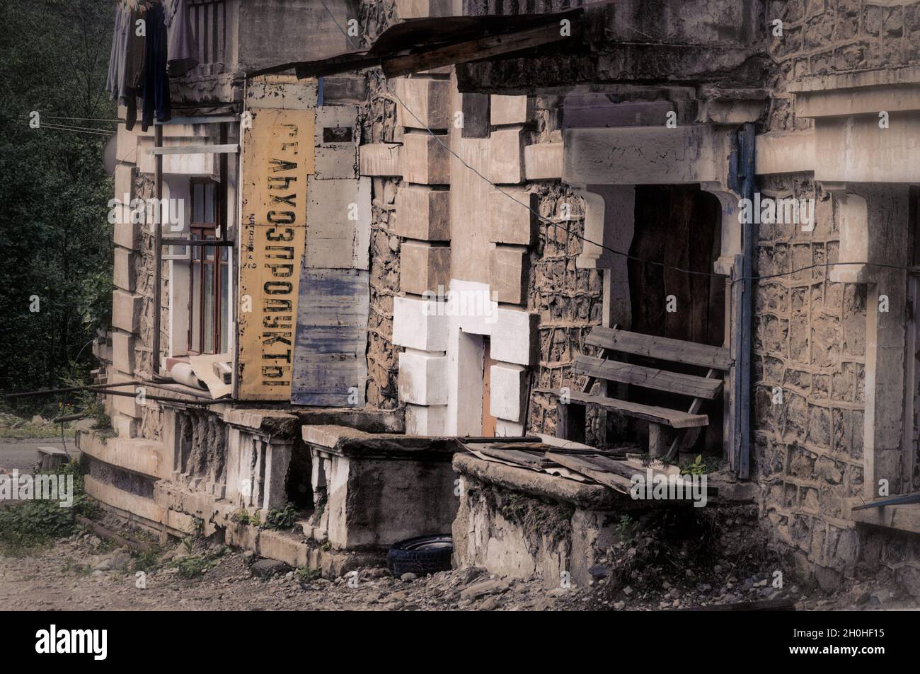 SADON, RUSSIA - 07 25 2021: Vecchio edificio abbandonato in rovinato da fango piccola città alta in montagna con vecchio segno sovietico Grocery Store 2 in russo Foto Stock