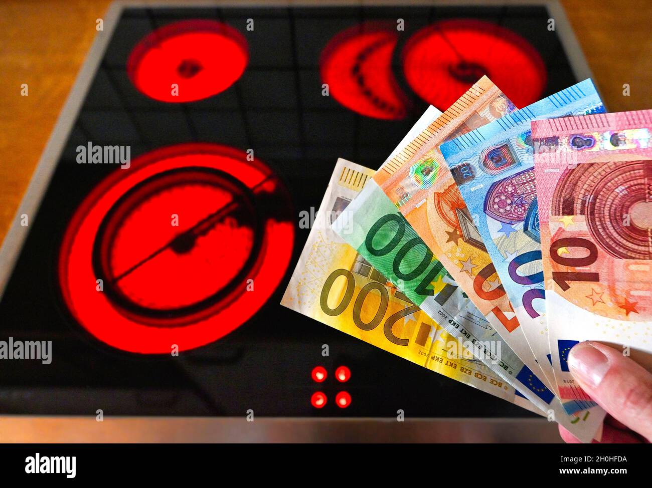Immagine simbolica aumento dei costi energetici, piastra riscaldante, vassoi di denaro EURO Foto Stock