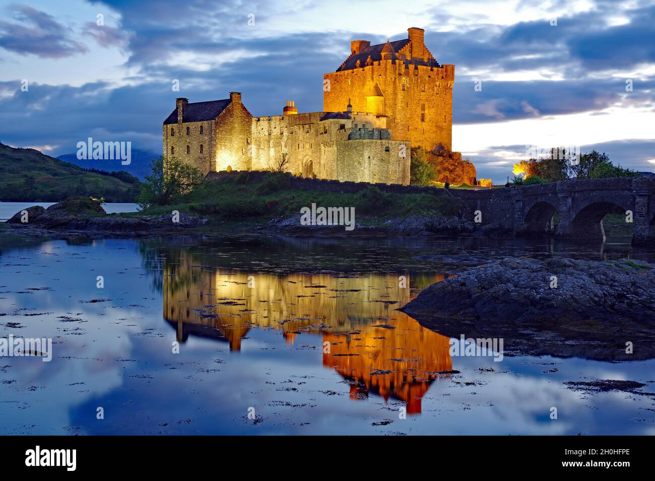 Castello con ponte è illuminato in modo diverso al crepuscolo, Eilean Donan Castello, Dornie, Highlands, Scozia, Regno Unito Foto Stock