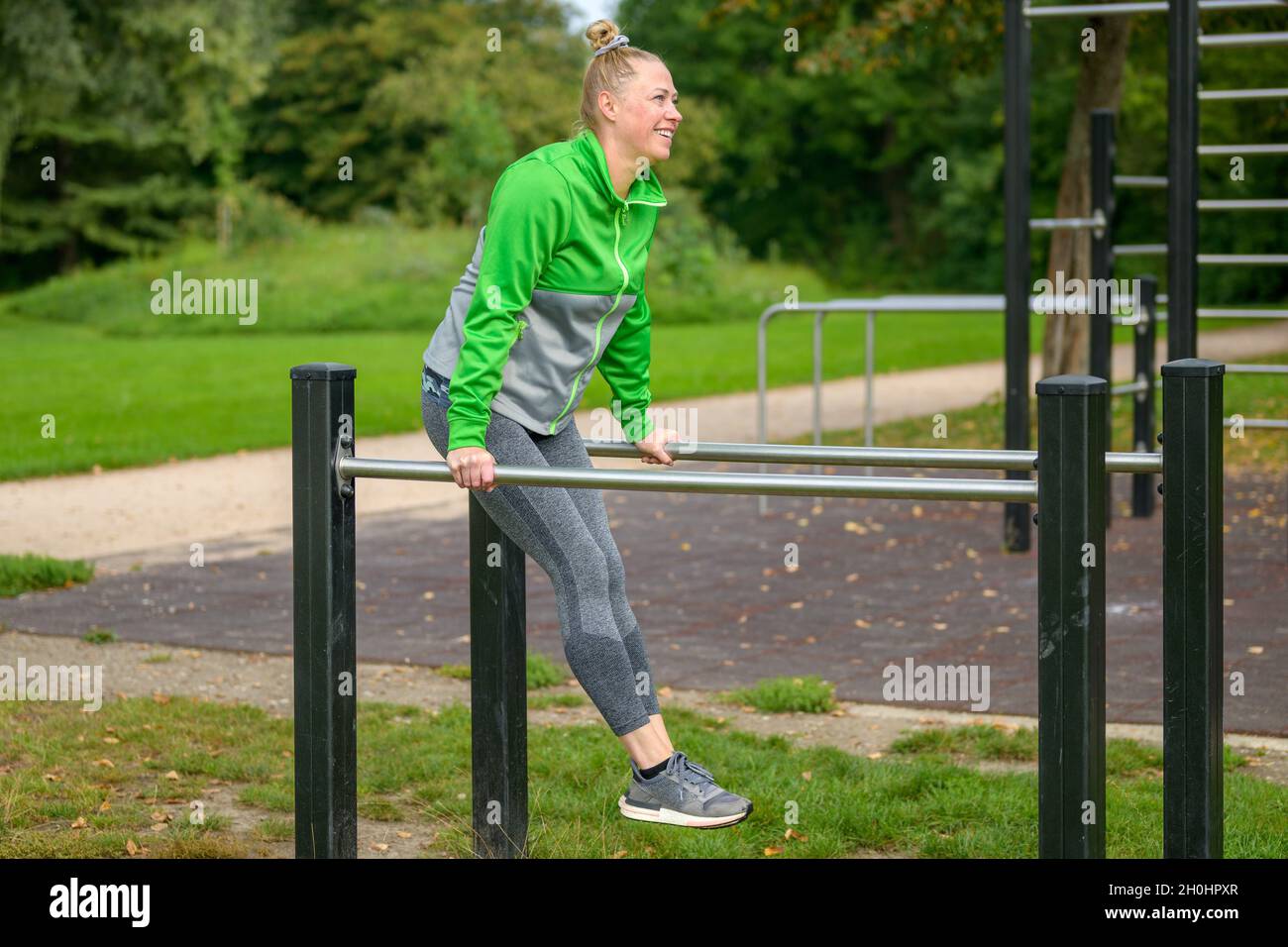 Donna sportiva di mezza età che si allena su bar paralleli in una struttura sportiva all'aperto in un parco in un concetto di salute e fitness Foto Stock