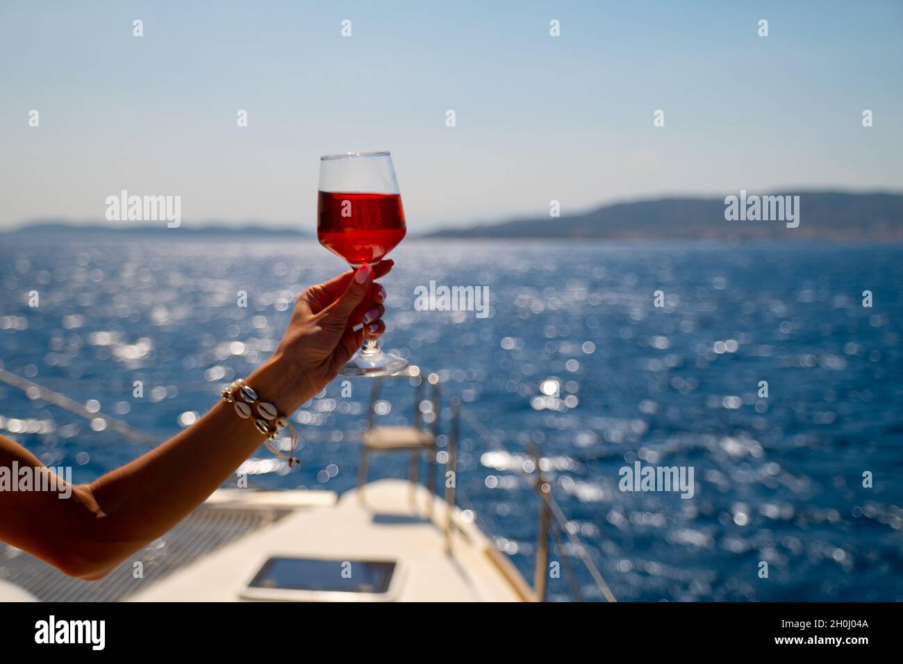Femmina di mano che tiene un bicchiere di vino sul background del mare Foto Stock