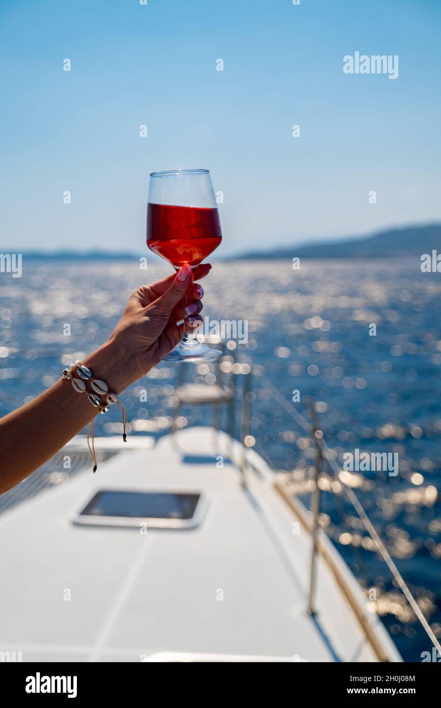 Femmina di mano che tiene un bicchiere di vino sul background del mare Foto Stock