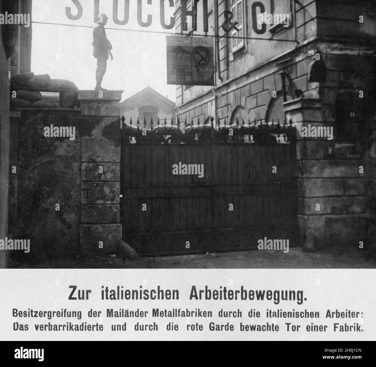 'Nel settembre 1920, i lavoratori italiani del movimento operaio socialista occupavano molte fabbriche dell'industria metallurgica, tra cui la fabbrica motociclistica Stucchi e C. in Via Tortona a Milano. Sotto la targhetta costruttore è appeso un poster con un martello e una falce e l'iscrizione ''Lenin''. Il cancello della fabbrica barricata è sorvegliato da una guardia Rossa. [traduzione automatizzata]' Foto Stock