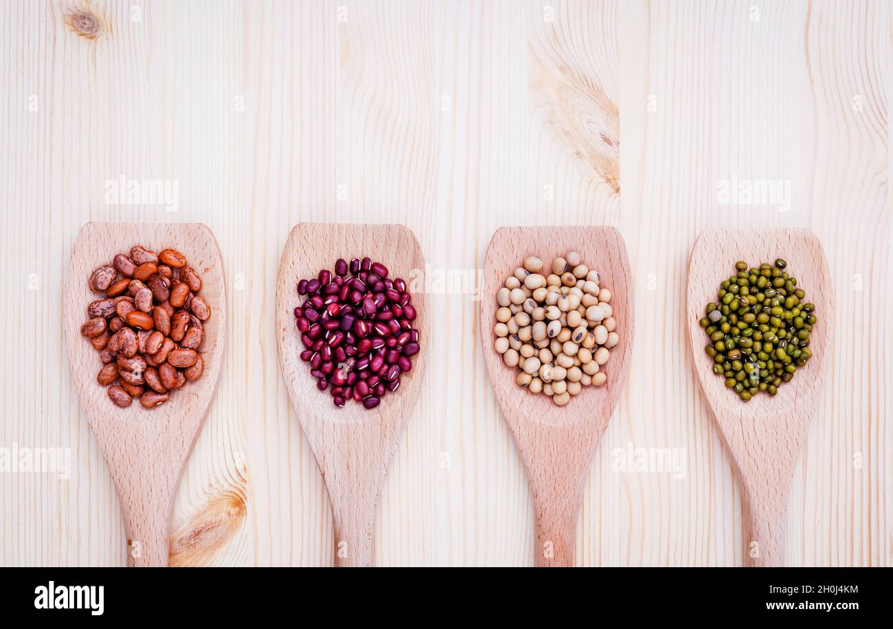 Assortimento di fagioli e lenticchie in cucchiaio di legno su sfondo di legno. semi di soia, Mung bean , Fagiolo rosso e marrone fagioli pinto . Foto Stock