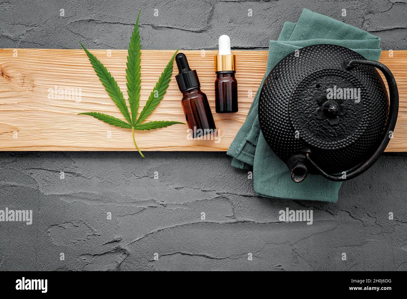 Teiera d'epoca con tè alle erbe alla cannabis e foglie di marijuana fresche allestite su sfondo concreto. Foto Stock
