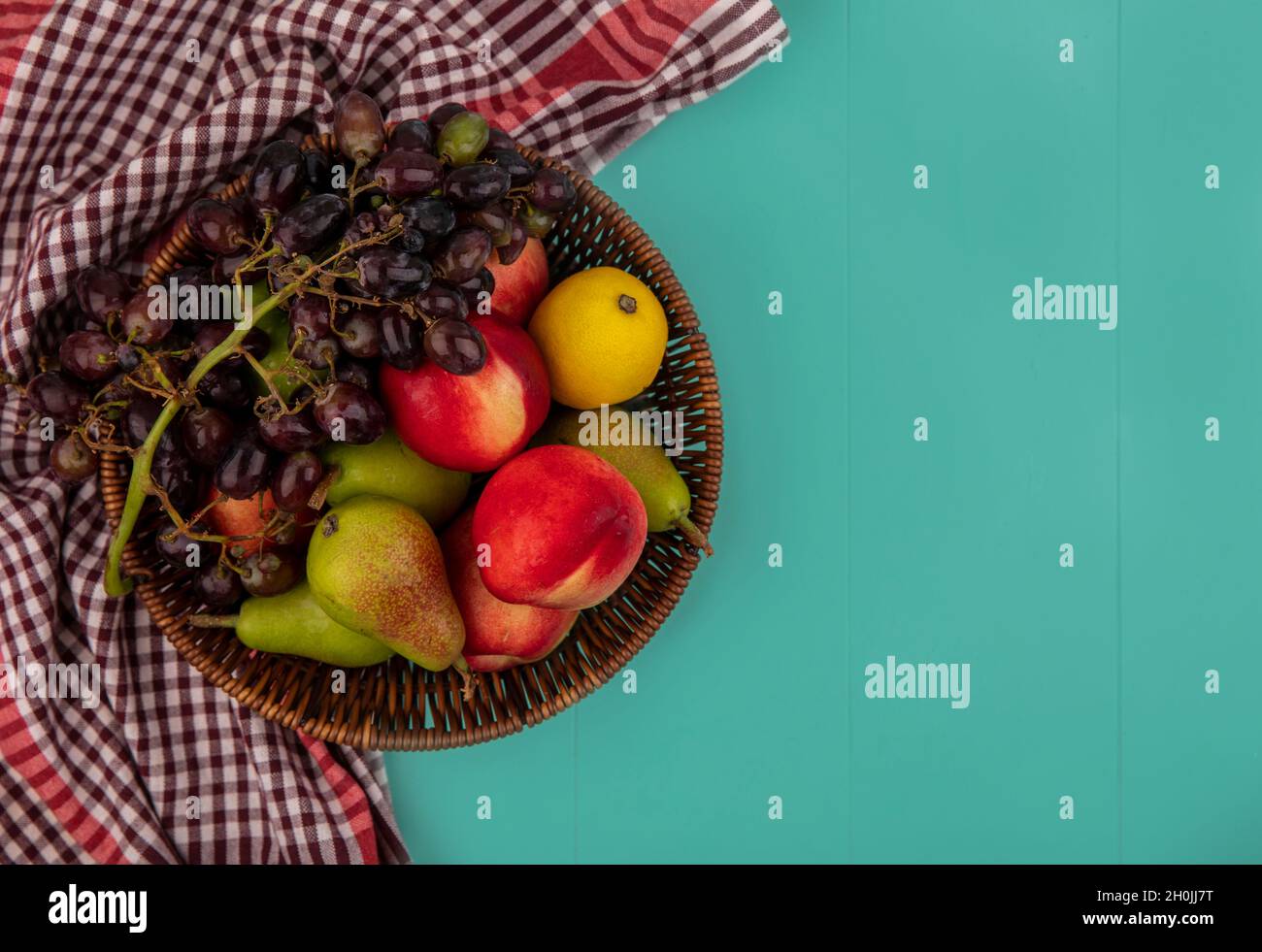 vista dall'alto della frutta come cestino di uva limone pesca pera su sfondo blu con spazio copia Foto Stock