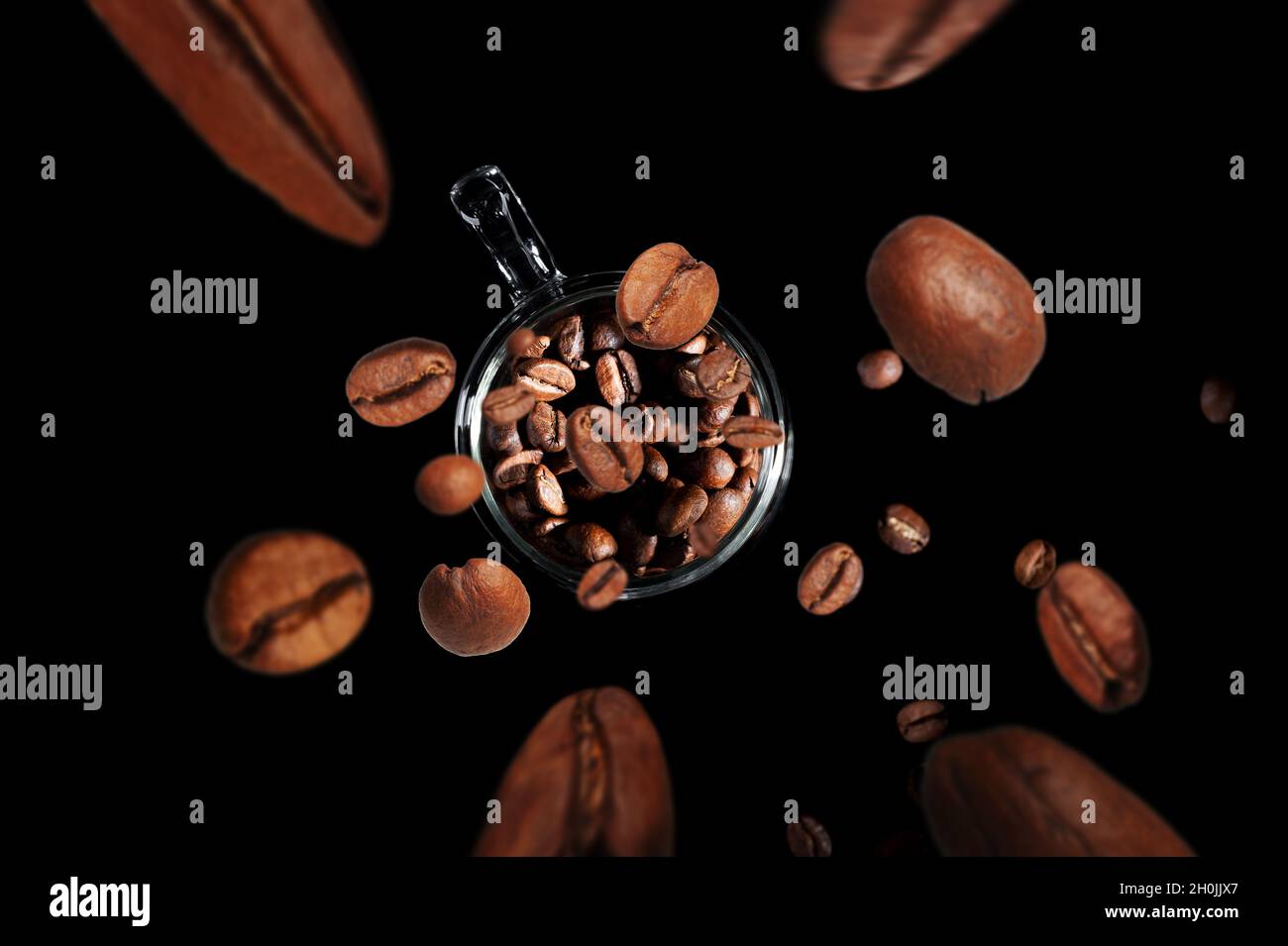 i chicchi di caffè volano in una tazza con il caffè isolato su sfondo nero vista dall'alto Foto Stock