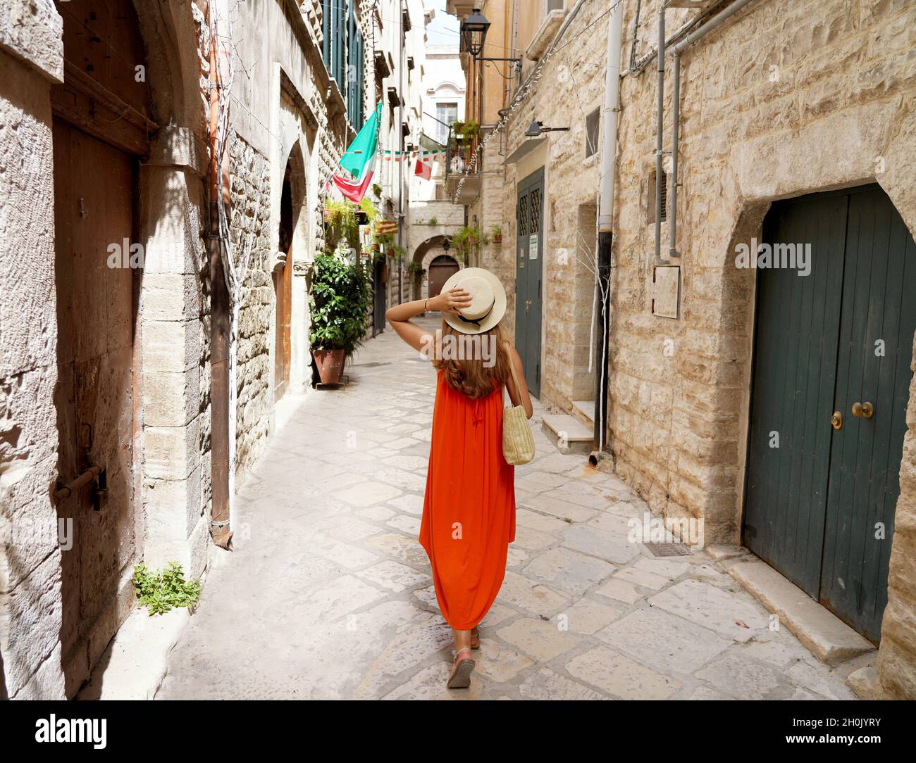 Donna con lungo abito estivo arancione a piedi nel vicolo stretto di  Bisceglie medievale città storica della Puglia, Italia Foto stock - Alamy