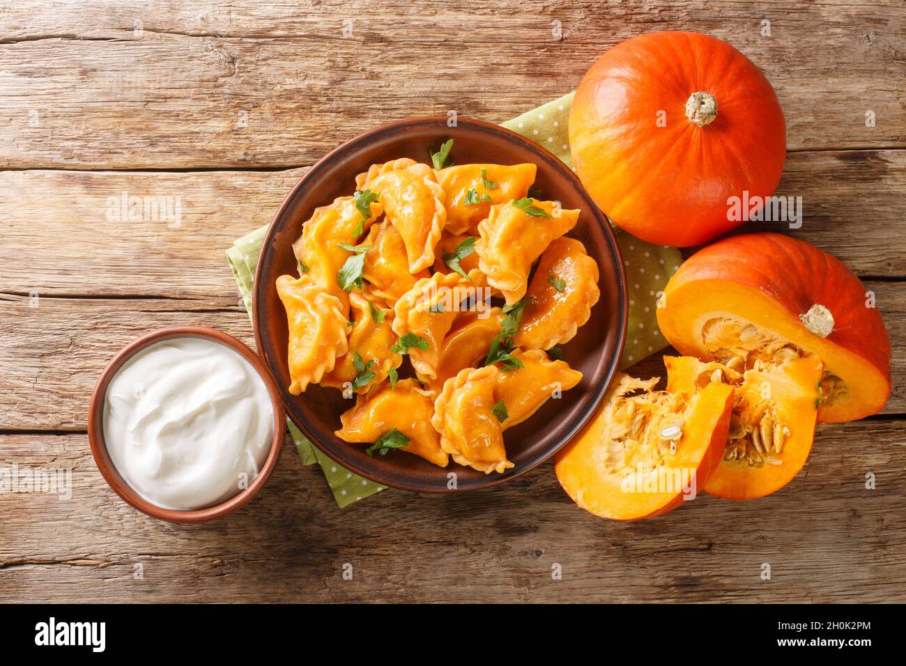 Deliziosi gnocchi di zucca d'arancia sani serviti con crema acida in primo piano in un piatto sul tavolo. Vista dall'alto orizzontale Foto Stock