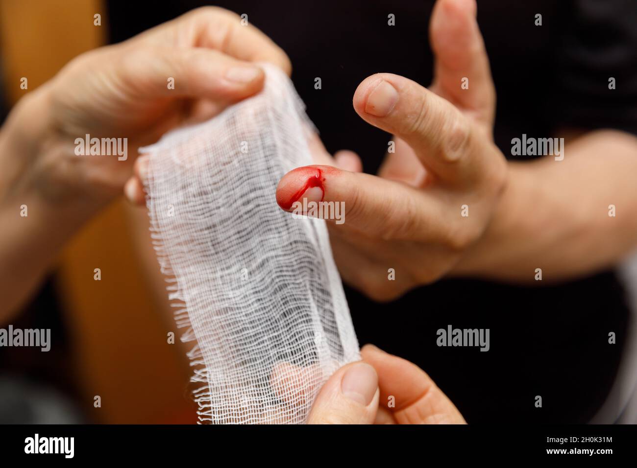 Applicare un bendaggio alla ferita del dito di un uomo. L'uomo trascurò le precauzioni e gli tagliò la mano. Trauma domestico. Lesioni da lavoro. Foto Stock