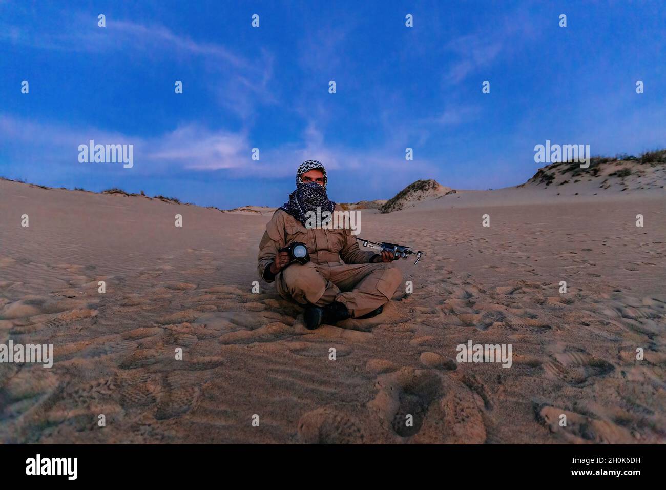 Terrorista nel deserto con drone e macchina fotografica. Concetto di procedimento penale per il blogging e falsa giustificazione del terrorismo. Foto Stock