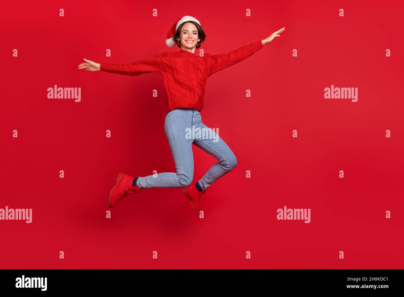 Foto del corpo di giovane ragazza eccitato felice sorriso positivo jumper vacanza noel isolato su sfondo rosso Foto Stock