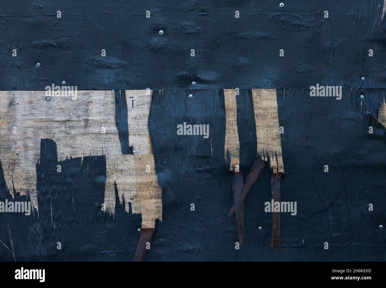 Sottile strato di legno visto peeling di legno compensato dipinto di nero che crea uno sfondo astratto. Foto Stock